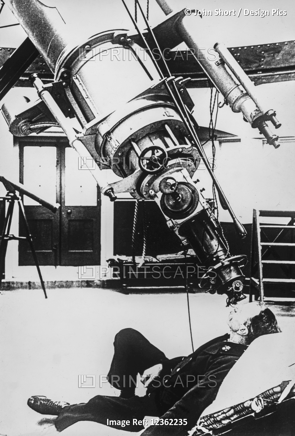 Historic image of a male astronomer looking through a large telescope