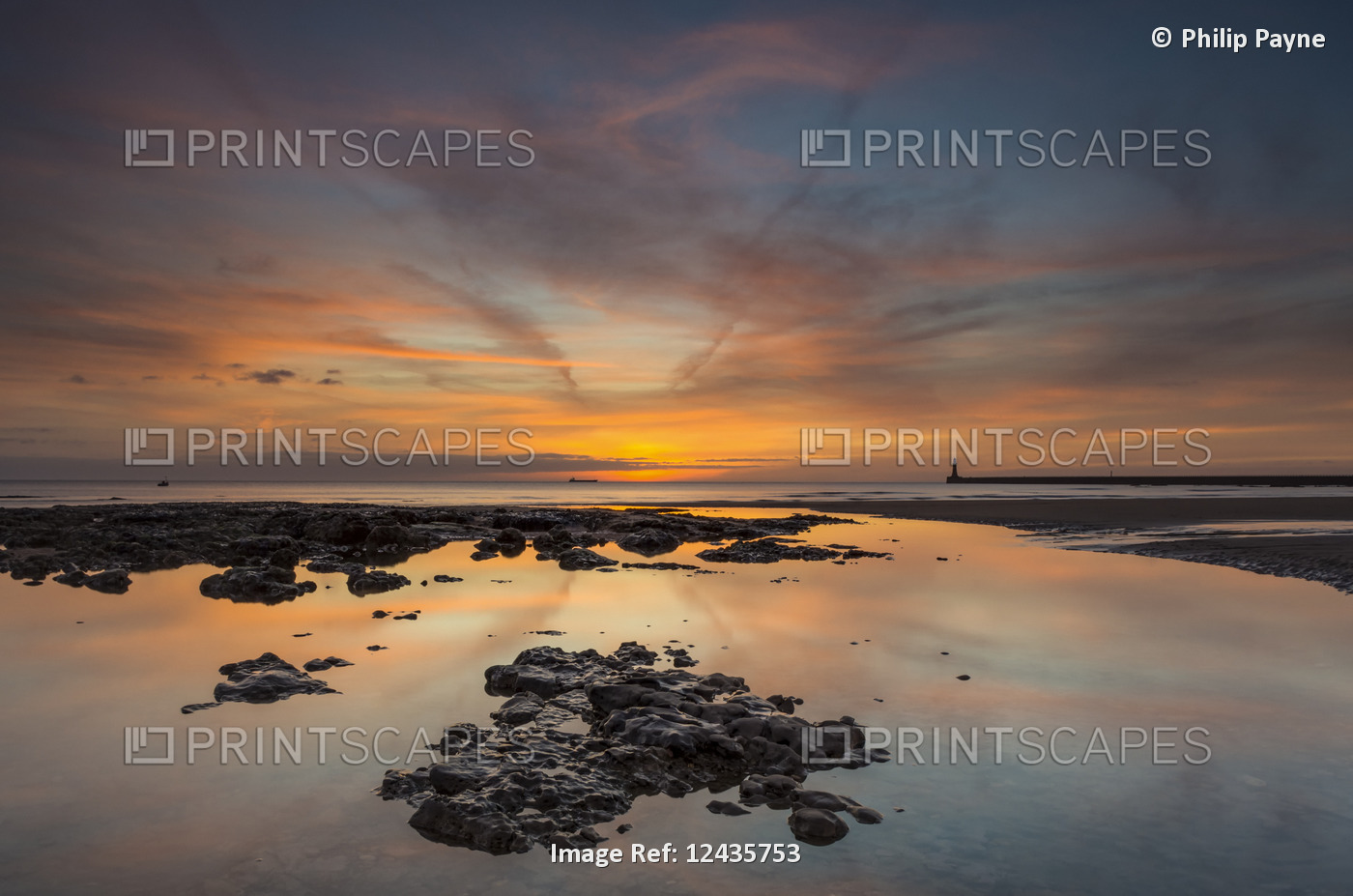 Sunrise reflections in a tide pool along the coast; Sunderland, Tyne and Wear, ...