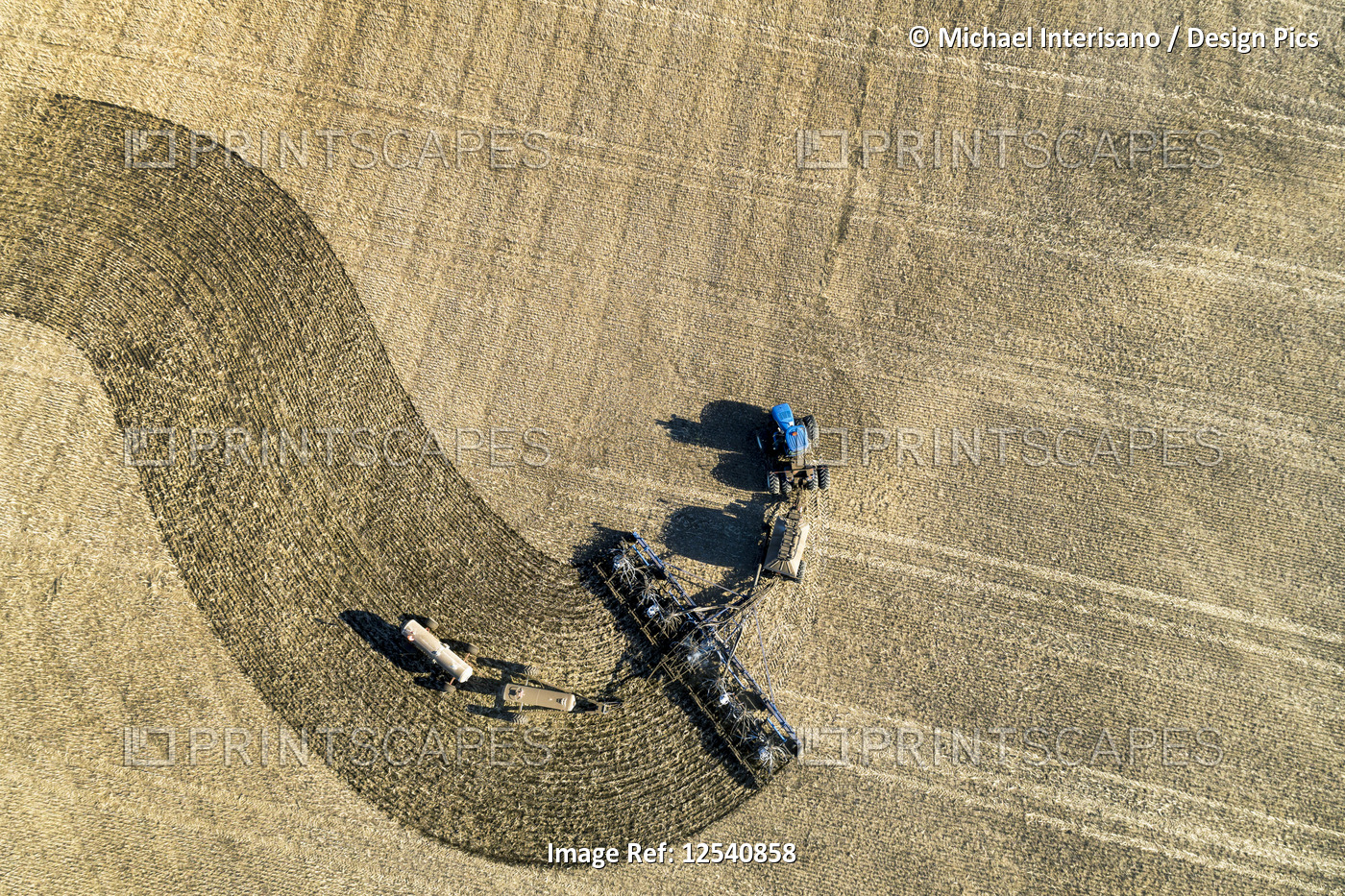 Aerial view of a tractor pulling an air seeder, seeding a field; Beiseker, ...
