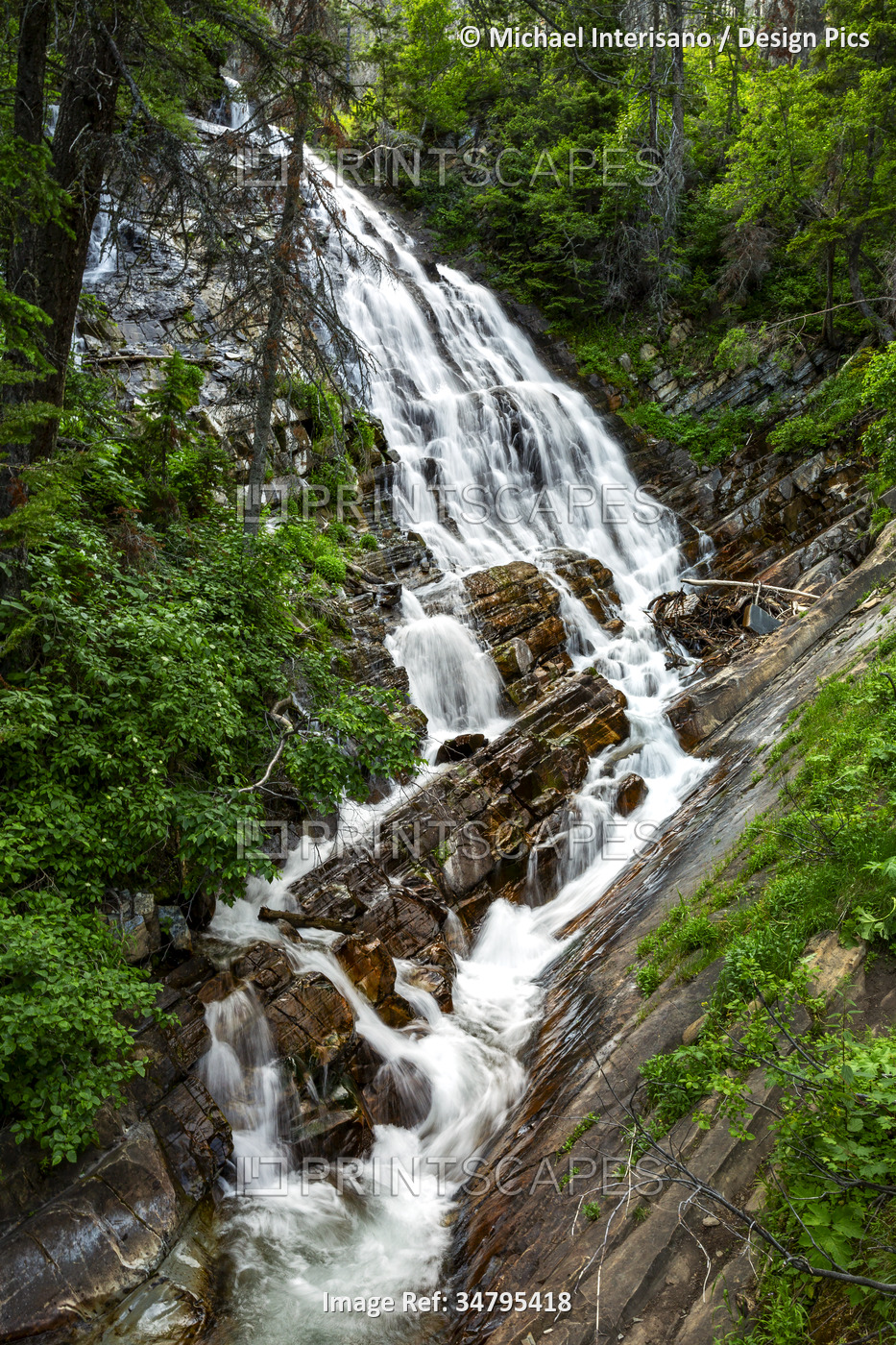 Cascading waterfalls against a rock cliff in the forest in Waterton Lakes ...